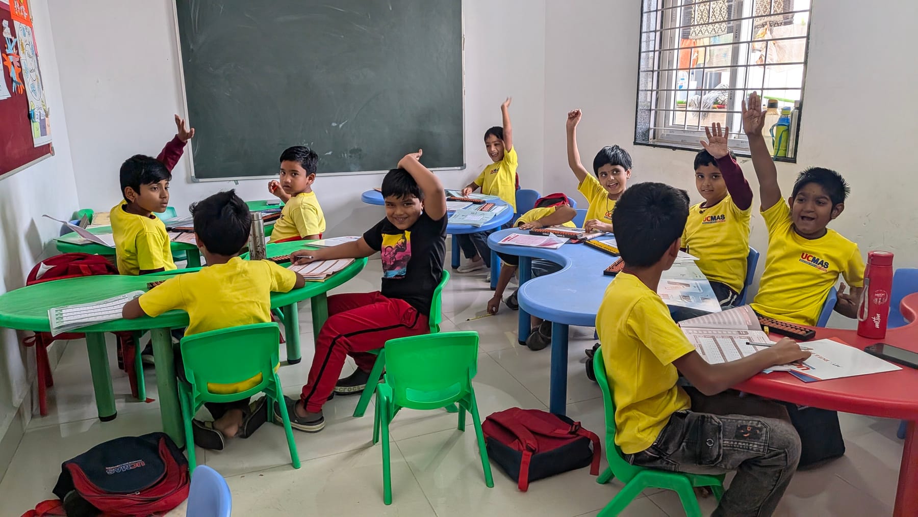 Children raising their hands to answer during an abacus class at UCMAS Beeramguda
